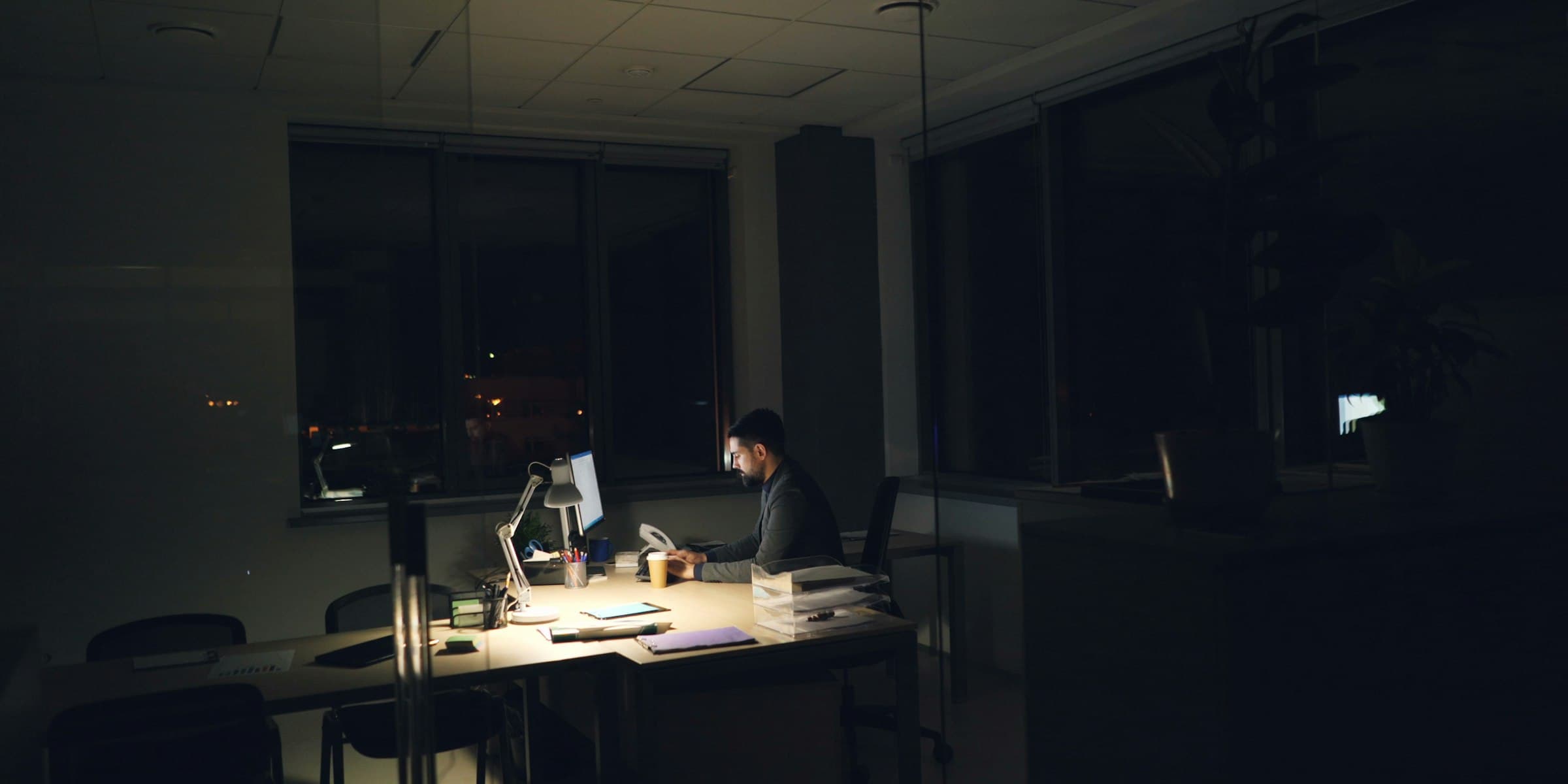 A founder working alone at a desk in a dark office at night